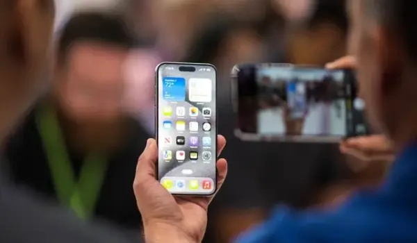 Pengunjung mencoba Apple iPhone 15 baru, dengan pengisi daya USB-C pesanan UE, ditampilkan di antara produk baru lainnya saat acara peluncuran di Apple Park di Cupertino, California, Selasa (12/9/2023). Foto: Nic Coury / AFP